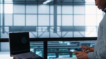 Technician with laptop and tablet integrating AI driven automation tools. Server room worker using artificial intelligence on devices, ensuring continuous uptime, camera A photo