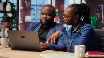 Young couple multitasking on laptop at desk, fully connected to internet, managing freelance work and remote responsibilities. Browsing web at home. Camera B. photo