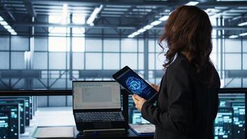 Technician with tablet integrating AI driven automation tools, running predictive maintenance routines. Woman ensuring continuous uptime of server room, managing data flows, camera B photo