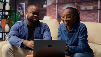 Couple in living room discusses creative ideas for online business, using modern technology to research trends and improve efficiency. Motivation and support for success. Camera B. photo