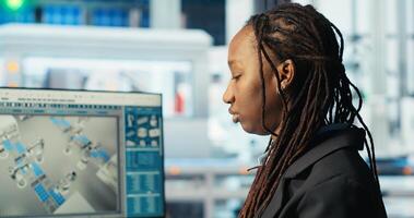 Factory programmer coding on PC to improve solar panels efficiency. African american software developer working in smart manufacturing plant, doing research, camera B photo