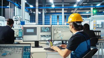 Factory engineer using PC to test robot arms placing solar panels on assembly lines. Professional sitting at computer desk inspecting photovoltaics machinery units, camera A photo