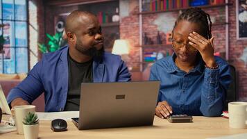 Worried woman looks at tax numbers on documents while partner reassures her, helping with financial planning. Discussing ways to reduce expenses, save money. Camera A. photo