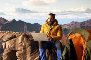 Nature lover workaholic always connected to internet and scrolling on laptop, enjoying web strong signal on mountain top with breathtaking landscape. Uninterrupted work. photo