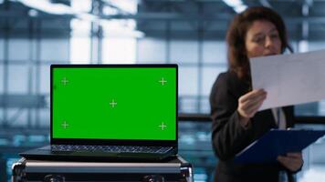 Green screen laptop used by data center admins in blurry background reviewing diagnostics. Chroma key notebook used by coworkers adjusting server room configurations, camera A photo