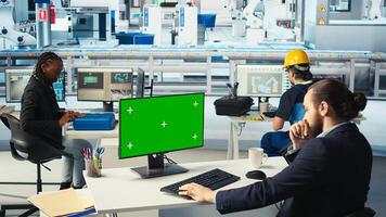Factory worker monitors system performance on green screen PC. Solar panels manufacturing plant employee using chroma key computer to track energy production and efficiency, camera A photo