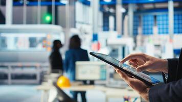 Engineer in photovoltaics factory using tracking software on tablet to diagnose malfunctioning systems. Solar manufacturing plant worker uses device to reduce downtime, camera A closeup photo