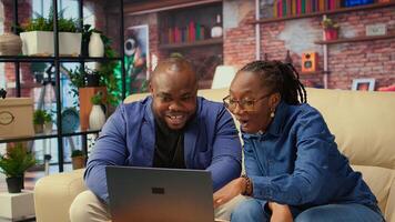 Freelancer couple doing research by reading articles and data driven papers at home, collecting information for new project. People multitasking and studying online reports on sofa. Camera A. photo