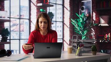Responsible lady paying bills and doing taxes on laptop, entering payment details on web and confirming money transfer. Online banking and finances from home office. Camera B. photo