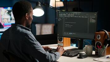 Black man programmer manages code and scripts in artificial intelligence and machine learning on dual monitors computer setup. Freelancer uses pc to guarantee cyber security. Camera B. photo