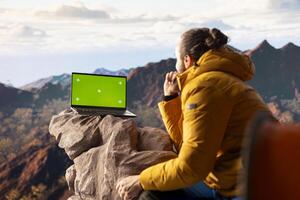Traveler embraces high altitude wilderness next to chroma key, using device where crisp air and scenic mountain view provide inspiring setting for trekking and adventure. photo