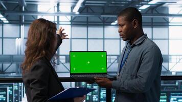 Engineering team using green screen laptop, implementing predictive analytics scripts, reviewing equipment health, adjusting system parameters and coordinating maintenance tasks, camera A photo