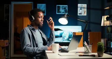 African American guy waving at call with workmates, working remotely from apartment and participating in executive meetings. Virtual communication. Camera A. photo