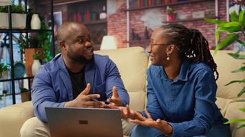africano americano autónomos en sofá compartiendo negocio idea, utilizando moderno tecnología y herramientas a analizar tendencias y aumentar éxito. Pareja mejorando flujo de trabajo eficientemente. cámara una. foto