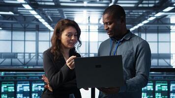 Engineers using laptop, managing server virtualization, running scripts. IT specialists using programming language on notebook in server hub, finetuning network protocols, camera B photo