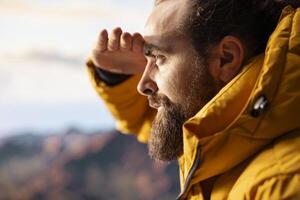 Determined traveler enjoying solitude of summit, where panoramic view represents adventure and personal growth. Hiker with outdoor gear feeling cold on windy mountain top. photo