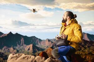 Young nature lover photographer recording mountain valley with drone, sharing hiking journey through vlog with high quality content with remote control. Hiker filming the scenery. photo