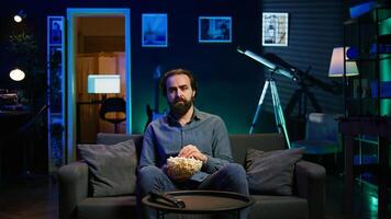 Sad man on couch feeling heartbroken while watching tragic movie on streaming service. Depressed person seeing TV show favorite character dying, showing emotional discomfort, camera B photo