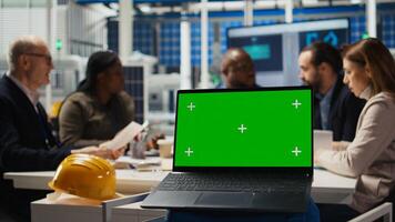 Shareholders in photovoltaics plant analyze market trends on green screen laptop to determine investment strategy. Managers look at data on chroma key device, expanding factory production, camera A photo