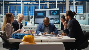 Engineering team looking at assembly lines designs, working to increase energy output. Photovoltaics experts brainstorm innovative solar cell prototypes, looking over schematics, camera A photo
