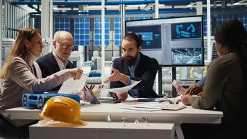Engineers study detailed schematics of solar panel assembly lines, refining layouts and component configurations for efficiency. Researchers outlining documentation for new prototypes, camera A photo