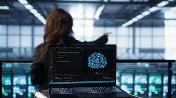 Laptop used by system administrators using artificial intelligence tech, handheld camera shot. AI programming language on notebook used by server farm employees, camera B close up photo