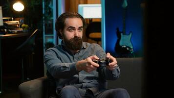 Man playing videogame in neon lit room, holding controller. Gamer participating in internet esports competition using professional gamepad for better victory chances, camera A photo