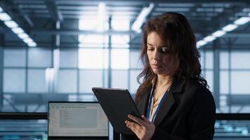 Technician in data center with tablet integrating AI driven automation tools, running predictive maintenance routines. Woman ensuring continuous uptime of server room, camera A photo