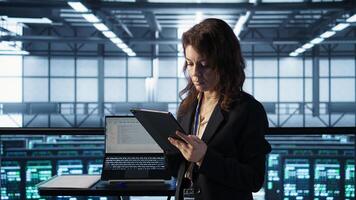 Technician in data center using AI tech on tablet, adjusting power management settings. Engineer in server room optimizes resource utilization using artificial intelligence, camera B photo