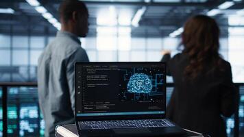 Artificial intelligence technology coding on laptop in data center with programmers in background employing machine learning models. Notebook used by AI experts, camera B close up photo