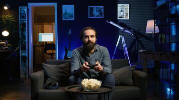 Smiling man putting headphones to play videogames on gaming console with teammates. Happy player enjoying defeating foes in game, discussing with friends through headset, camera B photo