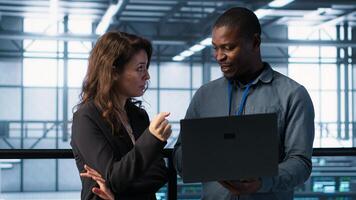 Engineers using laptop and managing server virtualization, running scripts. IT specialists using programming language on notebook in server hub, finetuning network protocols, camera A photo