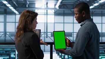 Software developers using mockup tablet, observing performance analytics charts. Server hub IT professionals talking, using chroma key device, looking over graphs, camera A photo