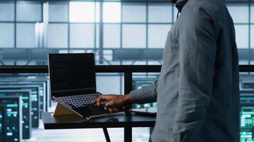 Technician in data center using AI on laptop and tablet, developing disaster recovery plans. Server farm employee using artificial intelligence tech on devices, testing scenarios, camera A photo