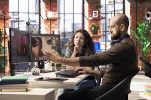 Graphic designer and photographer collaborate in a modern studio, using AI powered photo editing software on a PC. Providing automation, retouching and advanced image adjustment tools.