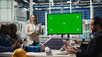 Engineers look over assembly lines schematics during business meeting in front of green screen monitor. Experts work on industrial plant configurations using mockup display, camera A photo