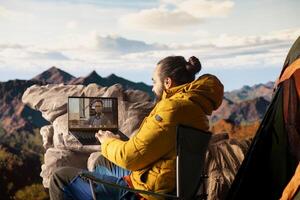 Workaholic explorer meeting with colleagues on online call, enjoying strong signal high speed internet on top of mountain. Young hiker entrepreneur with work dependency. photo