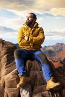 Explorer on mountain top taking in fresh air and panoramic scenery. Climber nature lover admires stunning landscape of rugged peaks and vast sky, adventure and sightseeing. photo