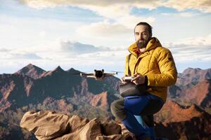 Male influencer shares hiking journey through vlog with drone, recording high quality aerial view content with remote control. Young hiker content creator filming scenery. photo
