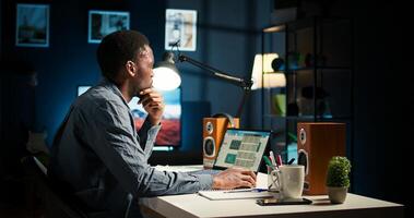 Remote worker balancing freelance tasks and researching data online, drafting notes and information for articles. Black person working at home, planning schedule and projects. Camera A. photo