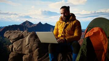Hiker with a technology obsession and strong signal working in nature, climbing the top of the mountain and connecting to work platform. Workaholic person enjoying internet everywhere. Camera A. photo