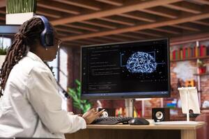 Freelancing computer engineer doing maintenance on artificial intelligence systems, listening music. Remote tech support specialist working from home wearing headphones, doing checkup on AI systems photo