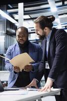Team of diverse engineers business partners evaluates solar performance in a modern industrial factory, focusing on sustainable development. Renewable power for sustainability. photo