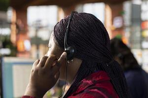 Call center agent in office using headset mic to answer customers questions, close up. Woman in customer support workspace in front of PC using audio headphones microphone to talk with clients photo