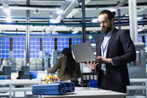 Engineer consultant in formal attire evaluates factory workflow, combining business expertise and industrial efficiency in solar tech manufacturing industry. Clean energy and innovation. photo