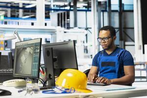 African american technician analyzing energy consumption software in solar factory, uses PC program to enhance solar cells production and reduce technical issues in automated machinery systems. photo