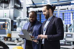 Team of diverse analysts consultants reviewing data and checklists in a high tech solar panel plant, ensuring manufacturing process meets sustainable energy and innovation standards. photo