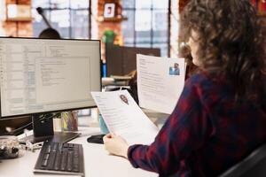 Startup HR worker identifying right candidates for job opening, reviewing resumes to determine qualifications. Woman doing screening process, selecting skilled people for software development position photo