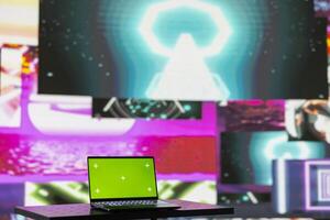 Laptop running isolated mockup screen surrounded by funky visual art clips, glowing in the dark and creating a clubbing atmosphere. Nightlife ambiance with modern beats and lights. photo