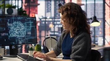 Female system admin doing maintenance on AI brain pc systems, sitting at office desk. Girl works as a software developer with cybernetics and algorithms for machine learning. Camera B. photo